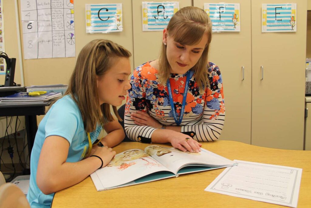 Education student reading with an elementary student