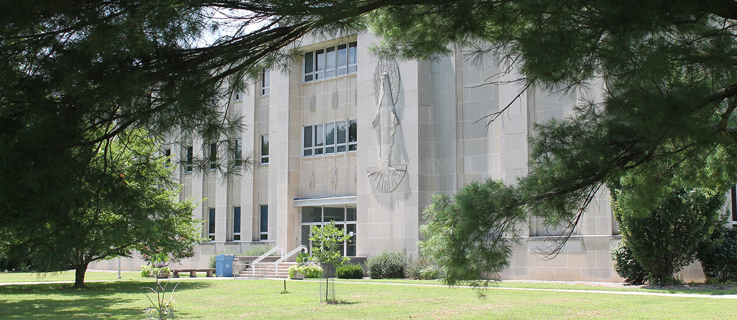 A view of Rooney Library surrounded by pine trees