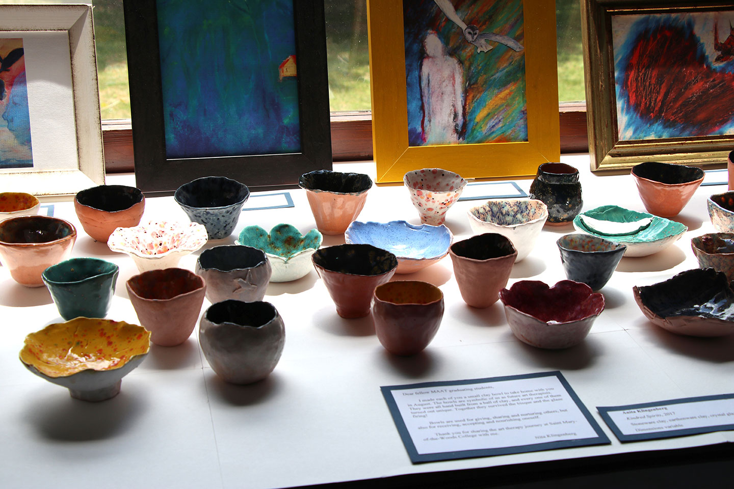 art exhibit with paintings and ceramic bowls