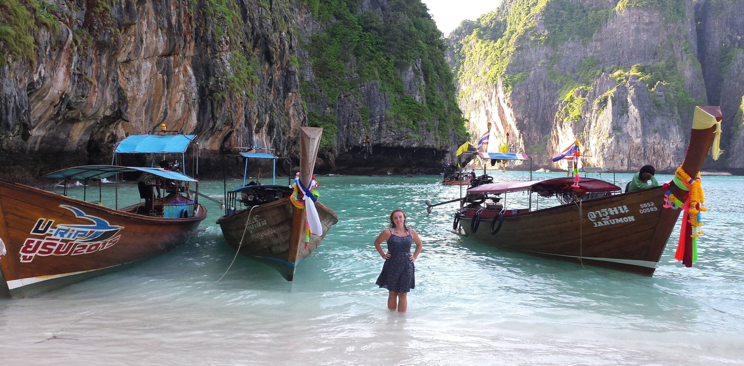 Student standing in water surrounded by boats