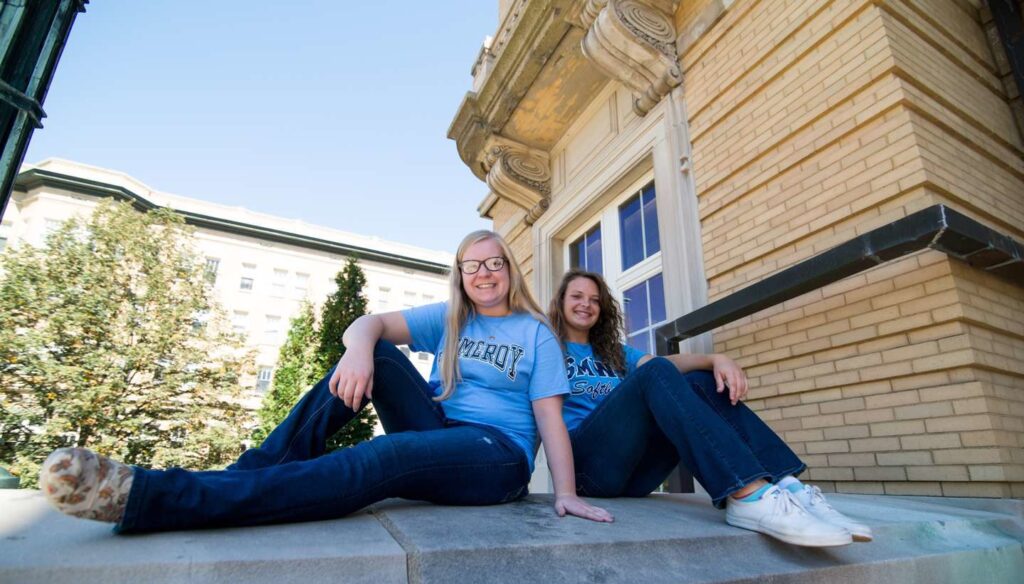 Two students sitting on steps of Le Fer Hall