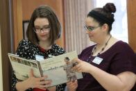 Two council representatives reading a book