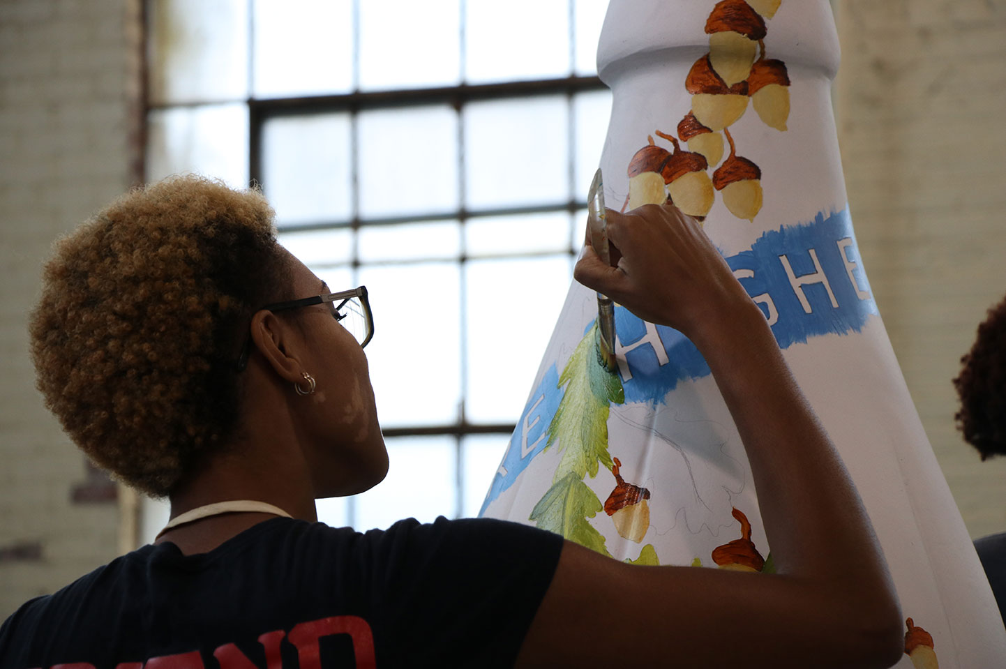 Closeup of Bry'Chell Johnson painting the bottle sculpture