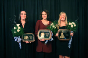 Erin, Stephanie and Jamie stand together holding their plaques at the Hall of Fame Banquet
