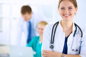 Young smiling nursing standing in front of colleagues in hospital setting