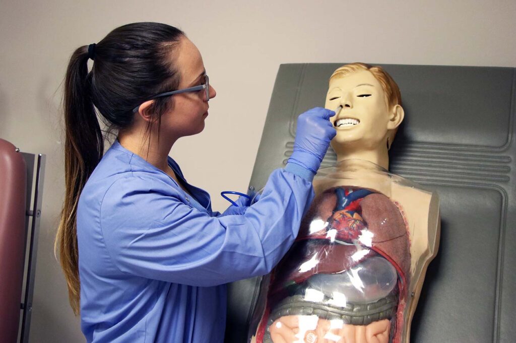 Nursing student placing breathing tube in the nose of a practice dummy