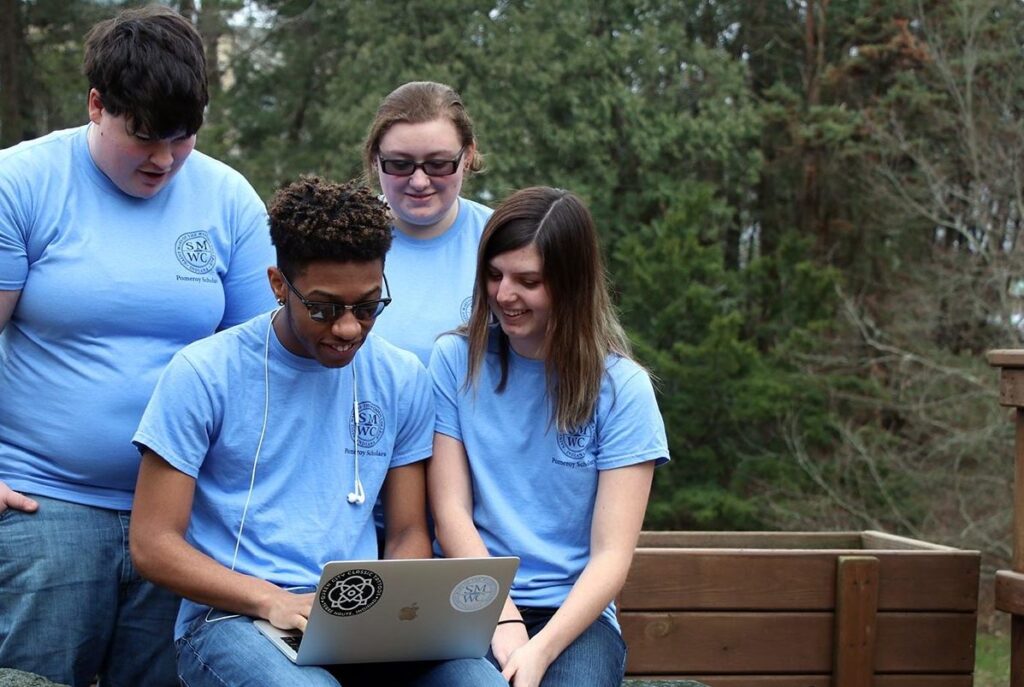 Group of Pomeroy Scholars looking at laptop