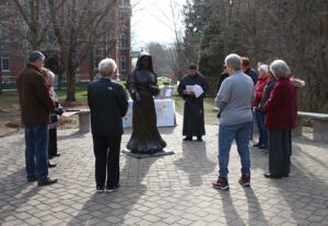 Group standing in a circle around the St. Mother Theodore Guerin statue