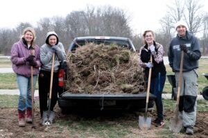 Tarasi standing with group of students in front of truck loaded up with sod