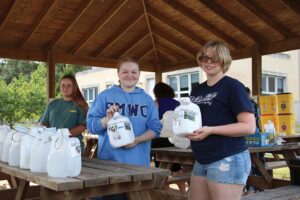 Students holding modified containers for cap recycling