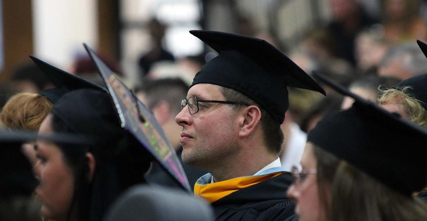 Graduates sit watching the commencement ceremony