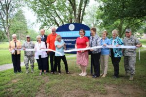 The project donors and sponsor stand in front of the Lake Le Fer sign holding a ribbon