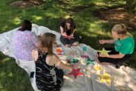 Group of MAMT students sit on a blanket painting stars.