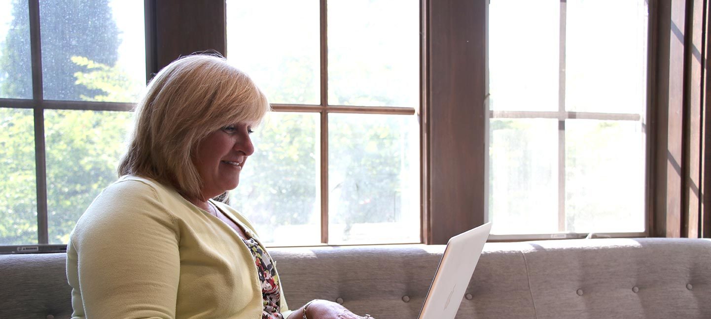 Amy Bridwell using laptop sitting in the Sullivan Parlor