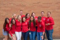 The group of interns laugh while standing for a group picture.