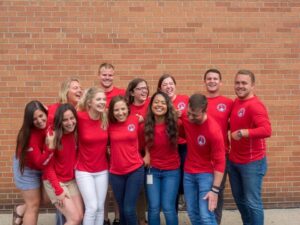 The group of interns laugh while standing for a group picture.