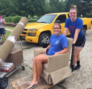 Taylor rolls a cart into Le Fer with Canada sitting on a chair in the cart.