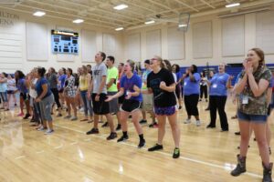 Students stand in the gym laughing during a Playfair activity.