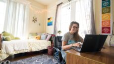 Student using laptop at their desk sitting in a dorm room