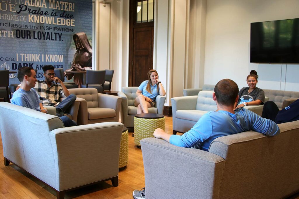 Students sitting in the middle of Sullivan Parlor smile and talk.