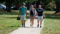 Group of three students walking up the path toward the library