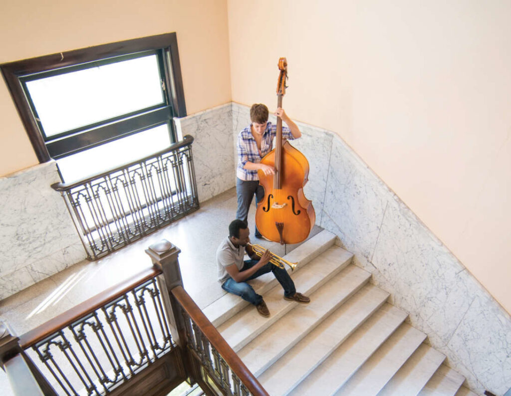 Students playing a trumpet and bass on the steps of the Conservatory