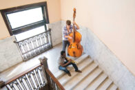 Students playing a trumpet and bass on the steps of the Conservatory