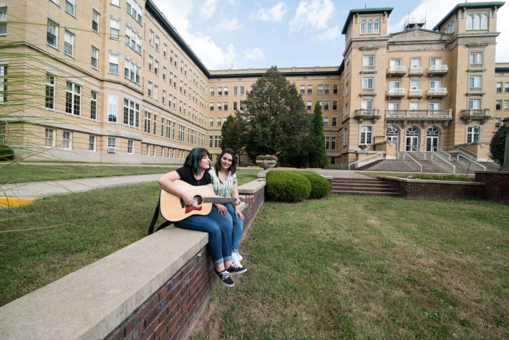 Students play guitar sitting on the walls of the Sesquicentennial Garden