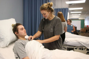 Basan holds a stethoscope to the chest of Cotter during a class exercise.