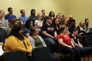 A large group of SMWC faculty and students listen to Ron Oates presenting in the Conservatory of Music.