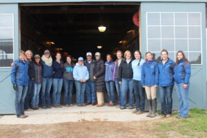 Hulman George stands with large group of students, faculty and staff in the doorway of the stables.