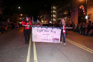 Ellis and Stuck leading the parade holding the banner and waving.