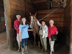The Harmans and their granddaughter stand with a horse in the SMWC stables
