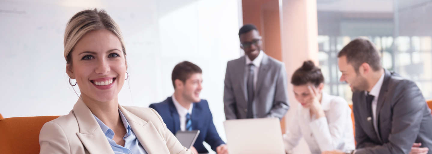 Smiling woman turned away from a group of professionals in meeting.