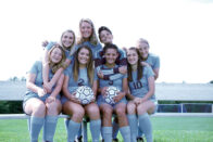 The soccer team siblings sit on a bench together at the SMWC soccer fields