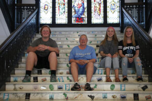 Simmons sitting in the same places on the main staircase of Le Fer Hall in 2018