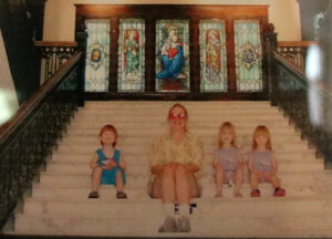 Old photo of Simmons with her triplets sitting on the main stairs of Le Fer Hall