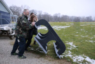 Student and staff pushing large plastic picnic table over.