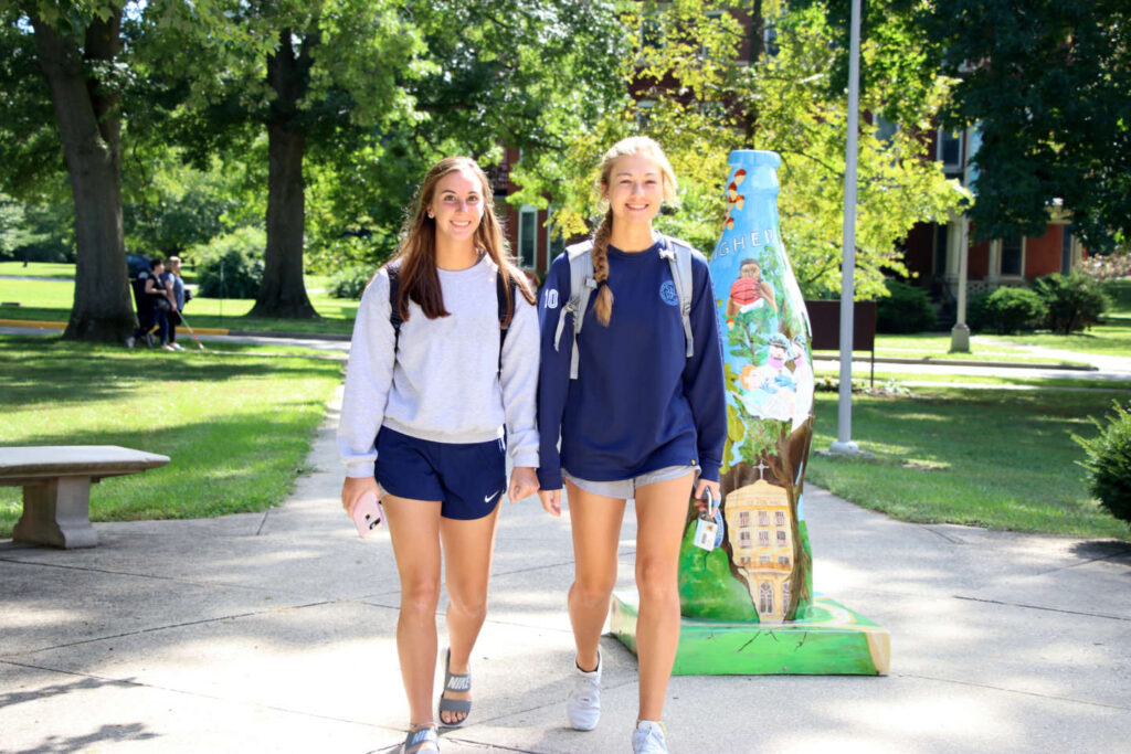 students walking by coke bottle statue