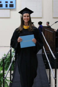 Kinon walking down from the stage holding her degree