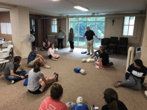 Students sitting in a circle, learning how to do CPR.
