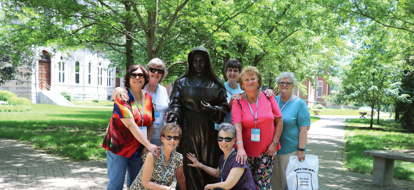 Alums standing with the SMTG sculpture