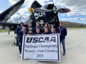 The women's cross country team holding their champions banner