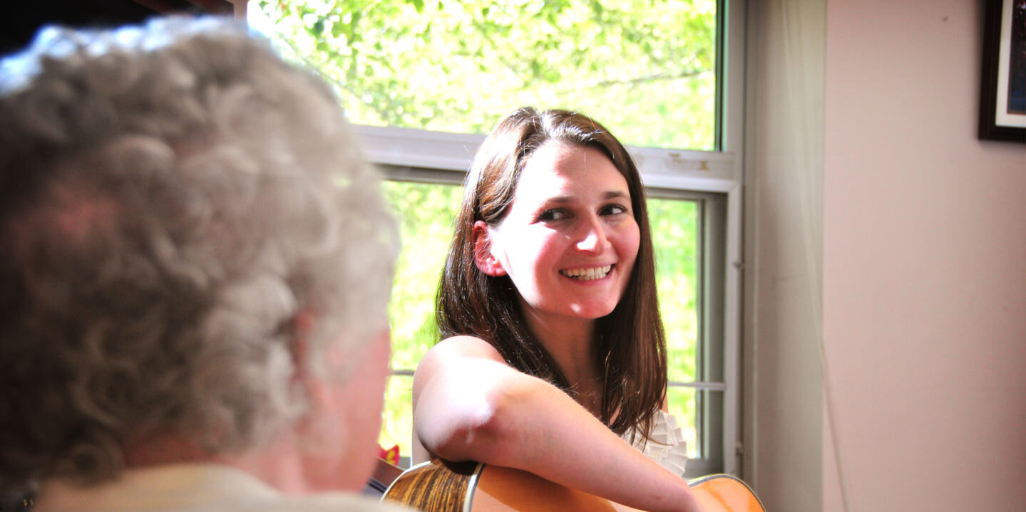 Music therapy student playing guitar for a senior