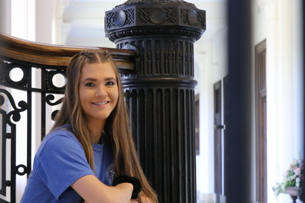 Smiling student sitting on the Le Fer staircase