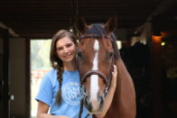 Smiling equine student holding the head of their horse
