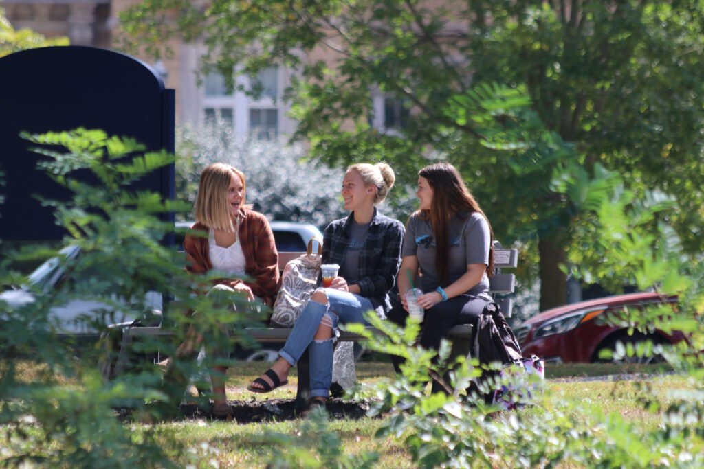 Smiling students on bench by the lake