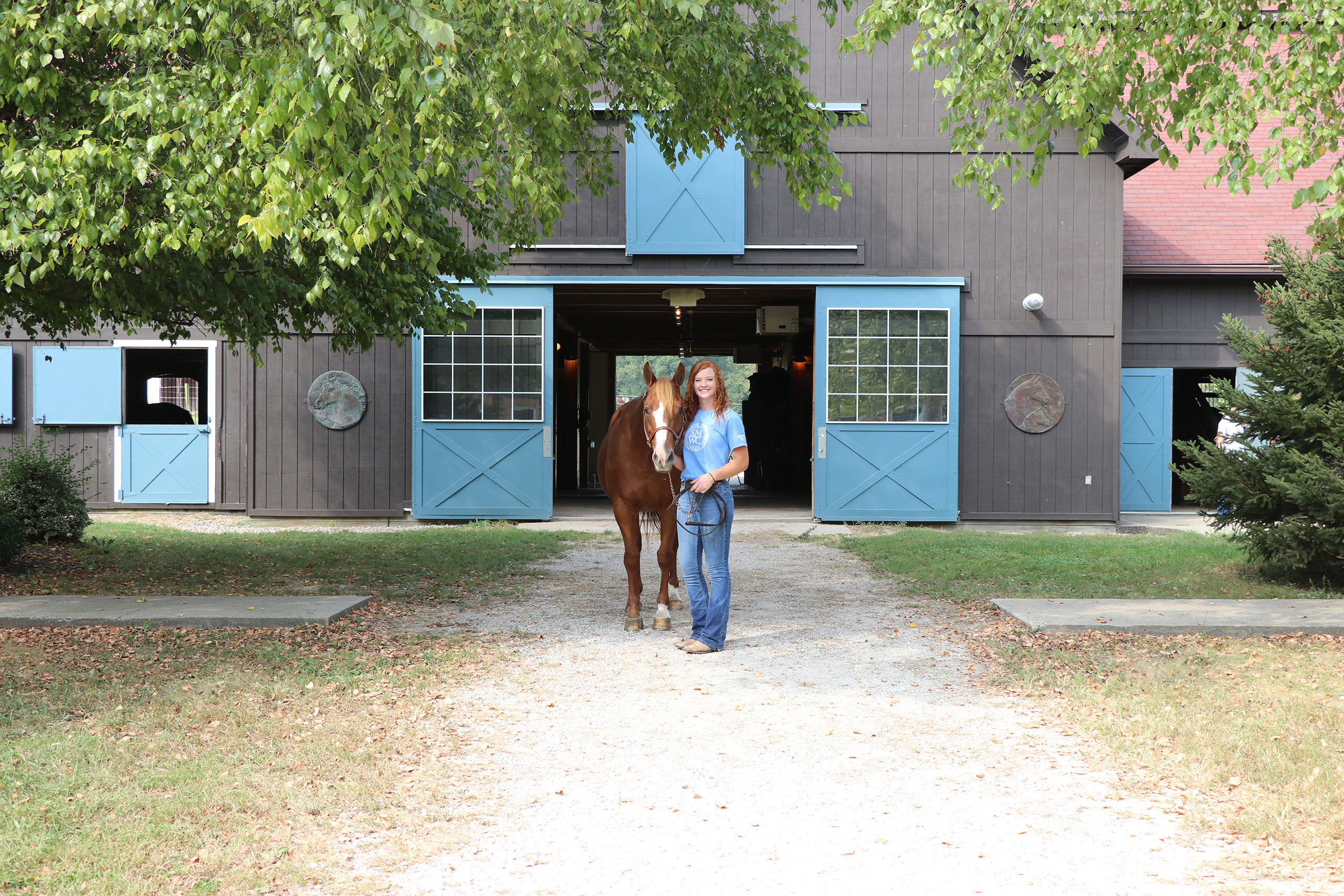 Student with horse in front of the stables