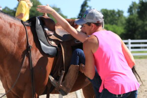 Schulz helping a camper onto a horse