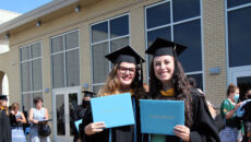 Graduates hold up their diplomas after the 2020 commencement